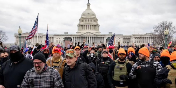 Proud Boys, many wearing orange hats, along with others outside the US Capitol on 6 January 2021